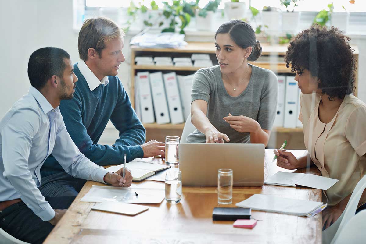 Four colleagues in a meeting around a laptop